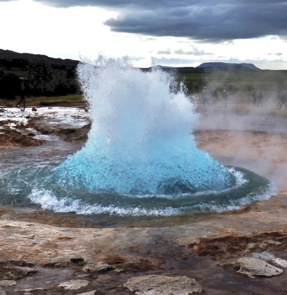 Geyser projetant un jet d'eau chaude et de la vapeur vers le ciel, illustrant l'eau sous forme liquide et gazeuse simultanément