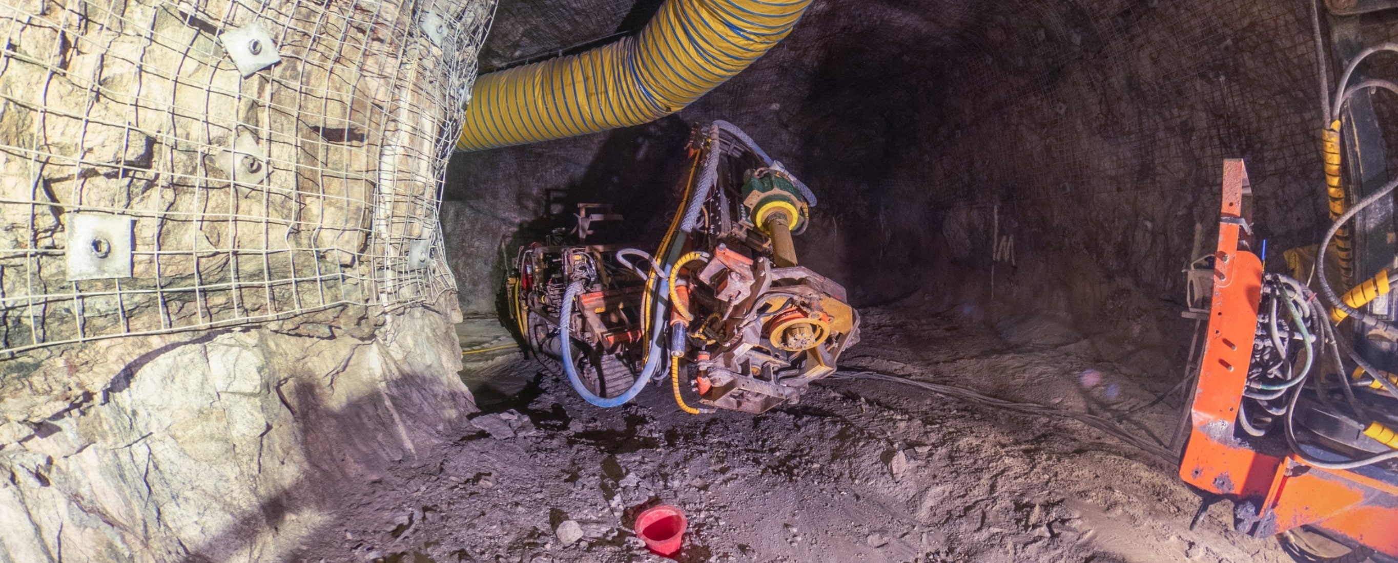 LA foreuse Foreuse d'exploitation opérant dans une galerie souterraine, équipée d'une tête de forage à pointes de carbure broyant la roche avec injection d'un mélange d'air et d'eau